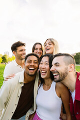 Vertical photo of happy young group of millennial friends having fun together outdoor. Millennial student people laughing, enjoying public holiday at city street.