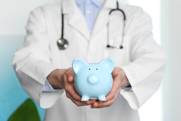Doctor with piggy bank in hospital, closeup