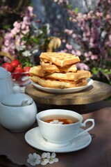 Beautiful spring flowers and freshly baked waffles on table served for tea drinking in garden