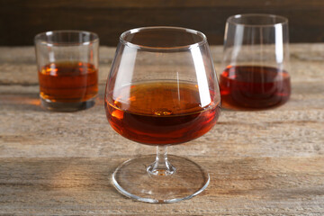 Different delicious liqueurs in glasses on wooden table