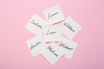 Paper stickers with different names on pink background, top view. Choosing baby's name