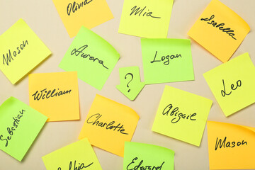 Paper stickers with different names on beige background, flat lay. Choosing baby's name