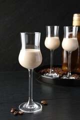 Coffee cream liqueur in glasses and beans on black wooden table