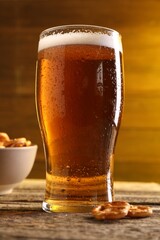 Glass of beer and pretzel crackers on wooden table