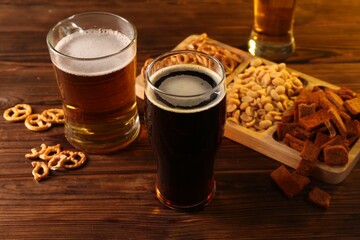 Glasses with different types of beer and snacks on wooden table