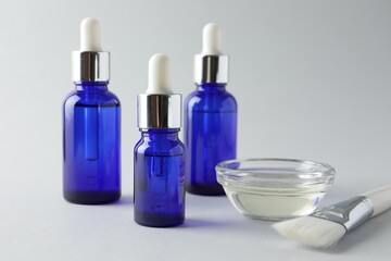 Bottles of chemical peel, bowl with liquid and brush on light background, closeup. Peeling procedure