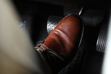 Man pushing on pedal of car brake, closeup