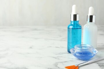 Bottles of chemical peel, bowl with liquid and brush on white marble table, space for text. Peeling procedure