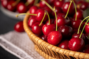 A closeup shot of a wicker basket brimming with fresh, red cherries.