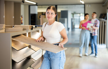 Female buyer chooses laminate flooring in a hardware store