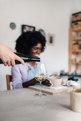 Cropped picture of hand pouring wine into wineglass on pottery class.