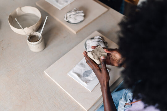 Top view of diverse pottery class student modeling clay at workshop.