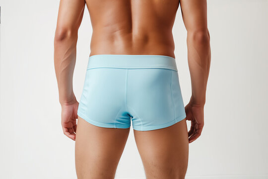 Male underwear concept. Close up studio shot of back of sportive athlete wearing light blue swimming briefs and isolated on white background.