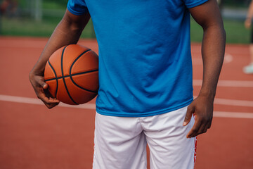 Multiracial player holding basketball at outdoor court