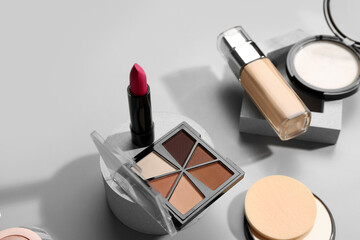 Stands with different decorative cosmetics on grey background