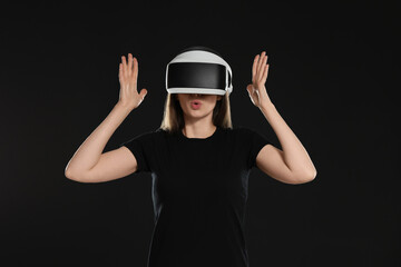 Surprised woman using virtual reality headset on black background