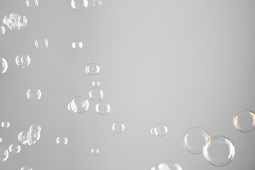 Beautiful transparent soap bubbles on grey background, space for text