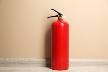 One fire extinguisher on floor near beige wall