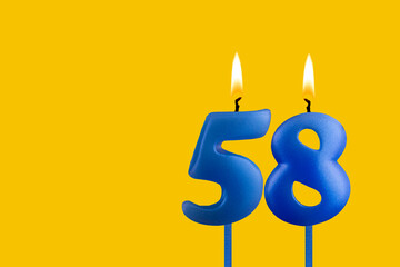 Blue birthday candle on yellow background - Number 58