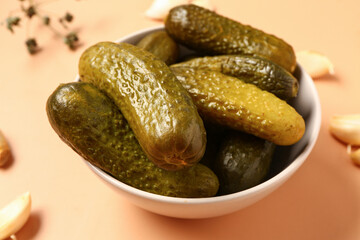 Bowl with tasty pickled cucumbers and garlic on orange background