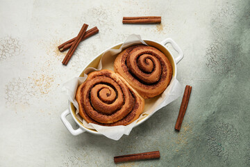 Baking dish with tasty cinnamon rolls on grunge background