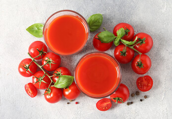 Tasty tomato juice in glasses, basil leaves, fresh vegetables and peppercorns on light grey table, flat lay