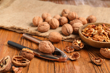 Bowl with walnuts and nutcracker on wooden background