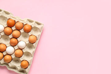 Chicken eggs in cardboard box on pink background