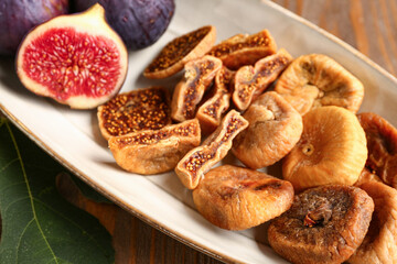 Plate with sweet dried figs and fresh fruits on wooden background