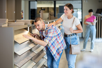 Positive interested young man and woman exploring various wood-look eco-friendly laminate...