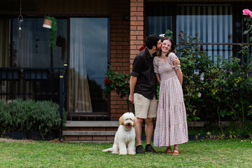 Aussie homeowner couple with pet tamaruke dog kiss in front of home