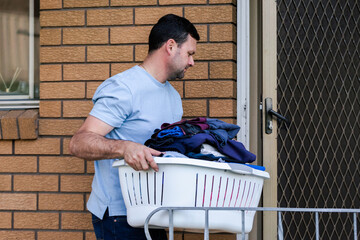 Man carrying washing basket inside through backdoor