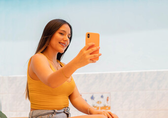 Mujer joven con polo top corto amarillo Hermosa mujer sonriente con teléfono móvil sosteniendo un...