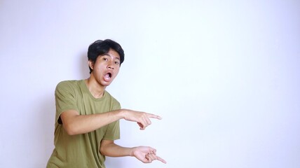 shocked young asian man pointing to the side on an isolated white background