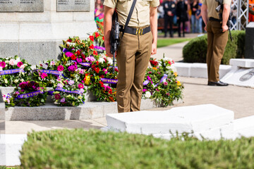 Australian soldiers standing by war memorial with wreaths laid around cenotaph on ANZAC day