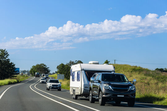 Car towing caravan on road trip through countryside on sunny day