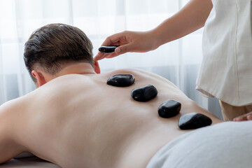 Hot stone massage at spa salon in luxury resort with day light serenity ambient, blissful man...