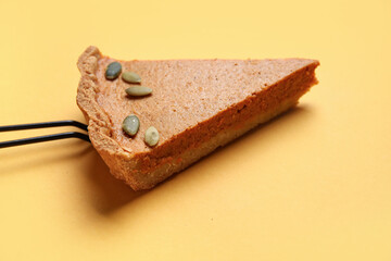 Piece of tasty pumpkin pie on yellow background