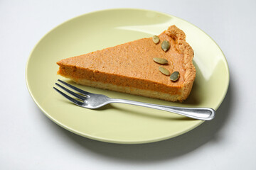 Plate with piece of tasty pumpkin pie on grey background