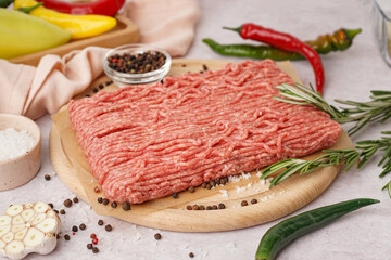 Wooden board of fresh minced meat with spices on white background