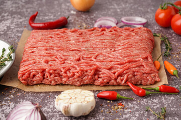 Fresh minced meat with spices on grey background