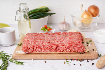 Wooden board of fresh minced meat with spices on white background