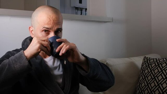 48 year old Brazilian man drinking tea, looking at the camera and grimace.
