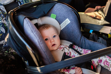 Four month old baby girl in car seat capsule buckled in for drive