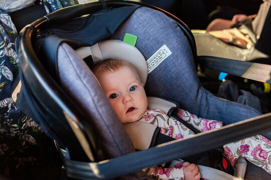 Four month old baby girl in car seat capsule buckled in for drive