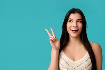 Young woman showing peace sign on blue background