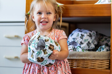 happy toddler girl holding cloth nappy by change table in bedroom