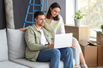 Young couple using laptop in room on moving day