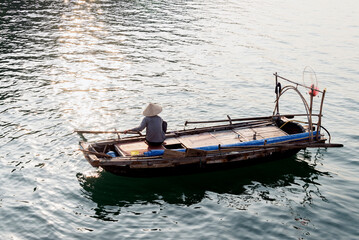 Naklejka premium Fisherman on his boat in Ha Long Bay, Vietnam