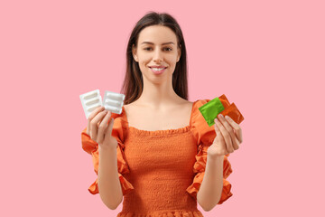 Obraz premium Beautiful young woman with condoms and vaginal suppositories on pink background